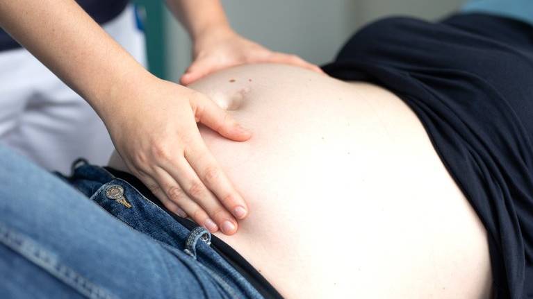 Billede af jordemoderstuderendes hænder der undersøger gravid mave